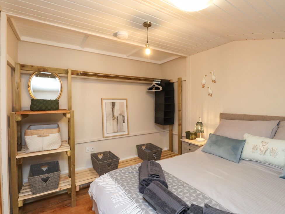 A bedroom with a bed and storage furniture at Woodman's Lodge in Llanallgo near Moelfre