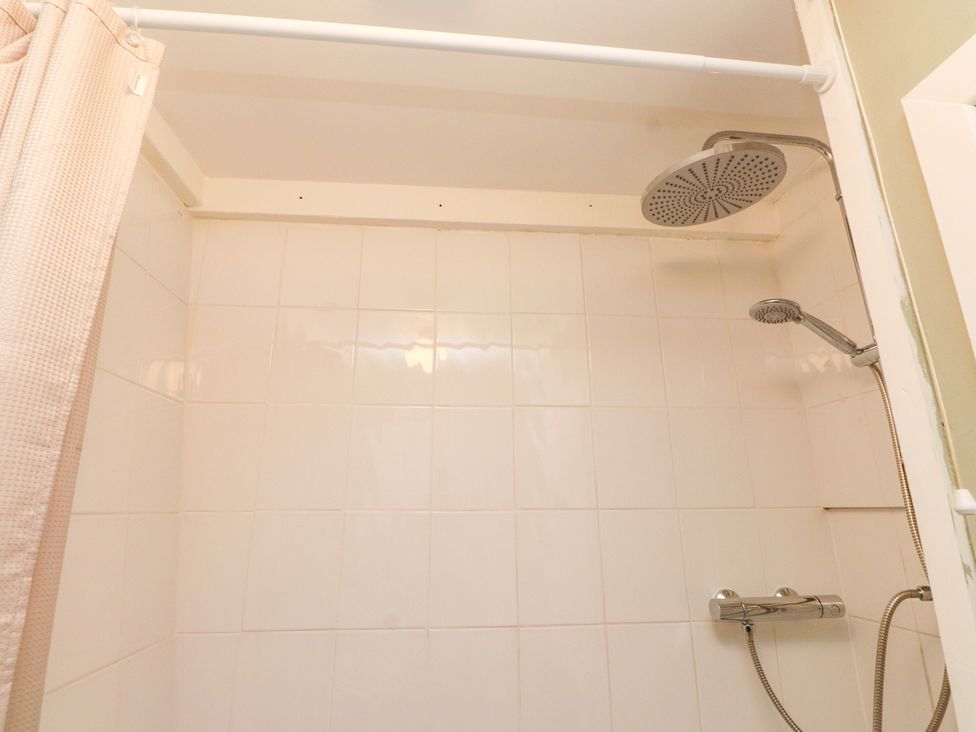 A shower with tiles and a curtain at Woodman's Lodge in Llanallgo near Moelfre
