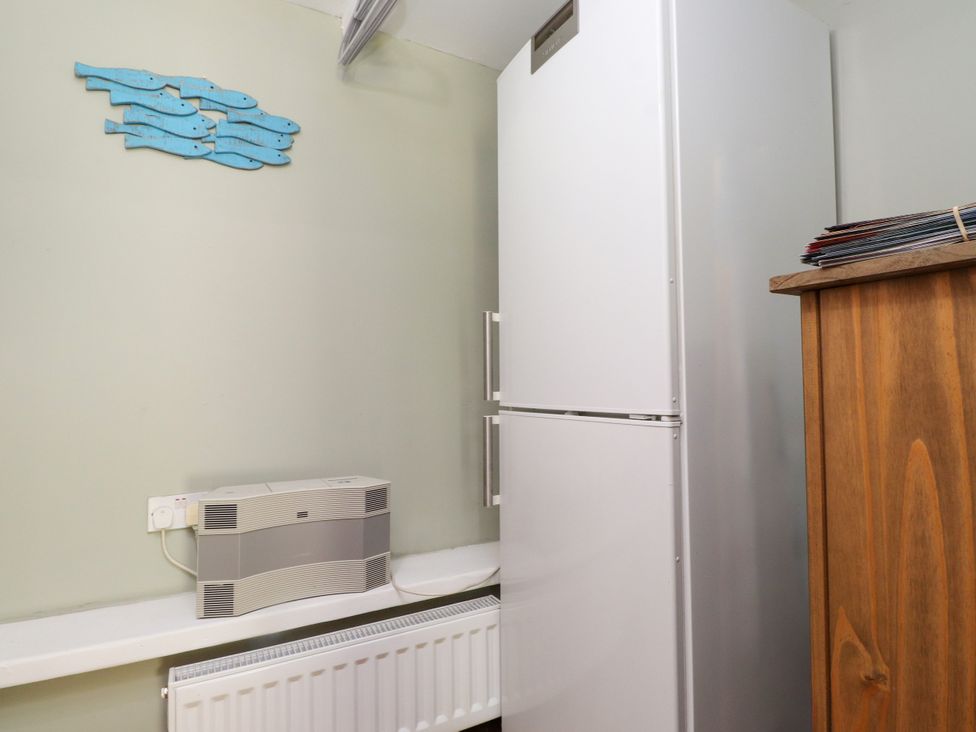 A kitchen with a fridge and a wooden cabinet at Woodman's Lodge in Llanallgo near Moelfre