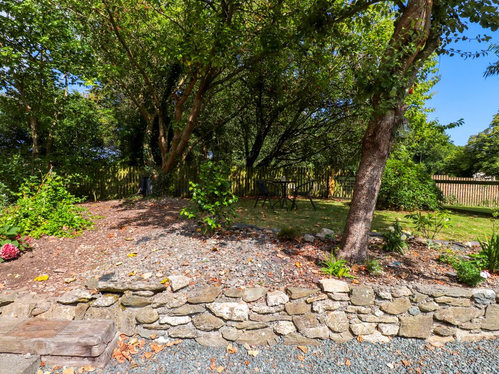A garden with trees and a table with chairs at Woodman's Lodge Llanallgo near Moelfre