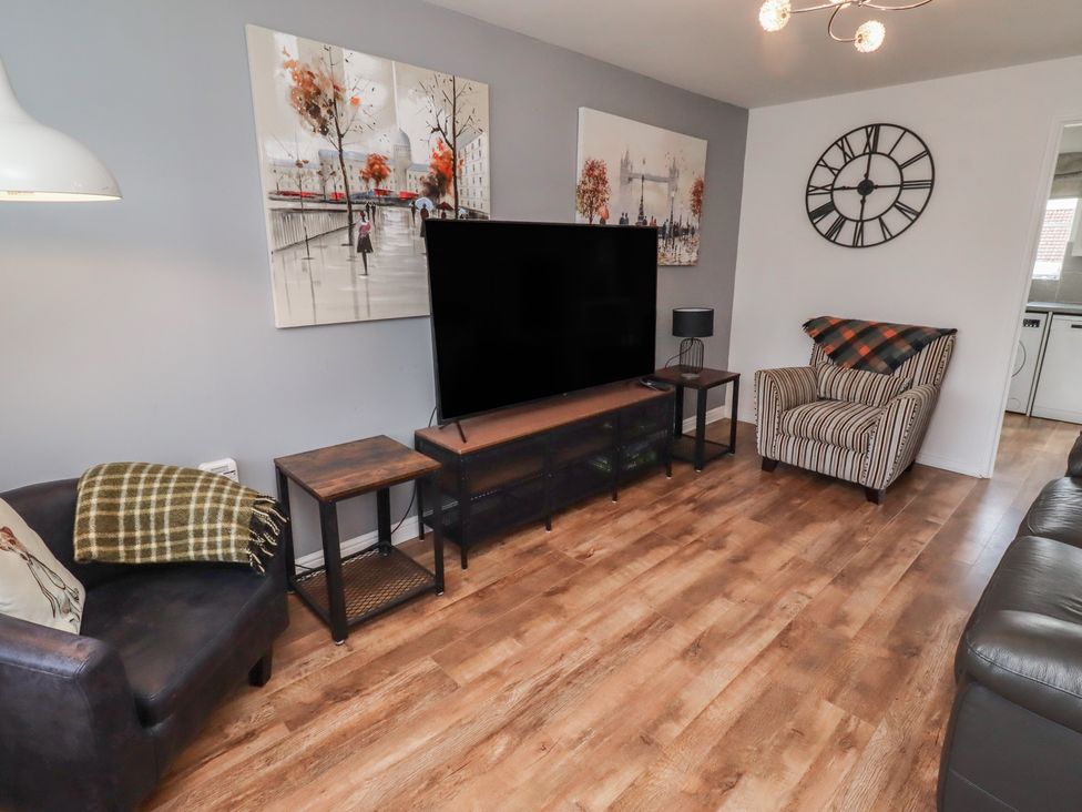 A living room with a television and seating areas at 26 Field Court