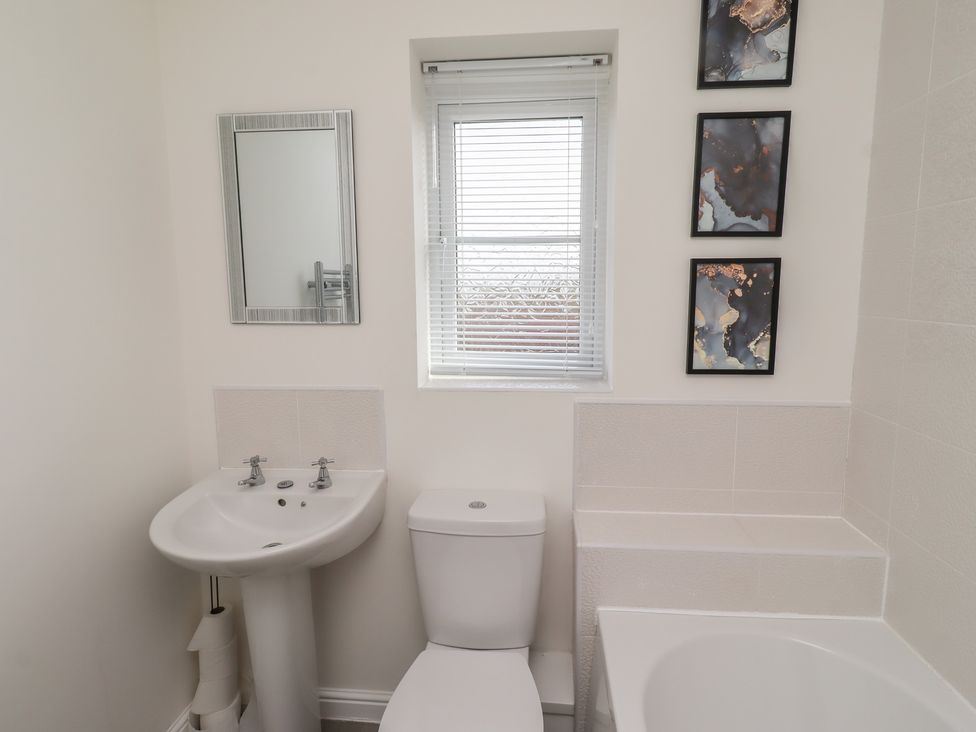 A bathroom with sink, toilet, mirror, and bathtub at 26 Field Court