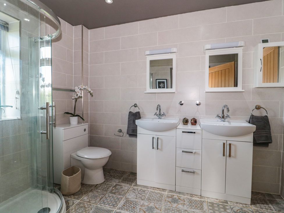 A bathroom with a shower, two sinks, a toilet, and mirrors at Annex at Barnfield House in Devizes