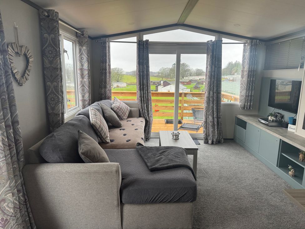 A living room with a sofa and television at Lochwood Platinum Superior at Three Lochs Holiday Park, Newton Stewart