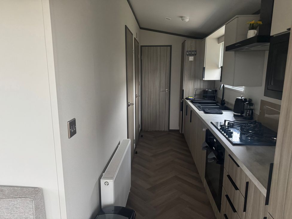 A kitchen with cabinets and appliances at Lochwood Platinum Superior at Three Lochs Holiday Park in Newton Stewart
