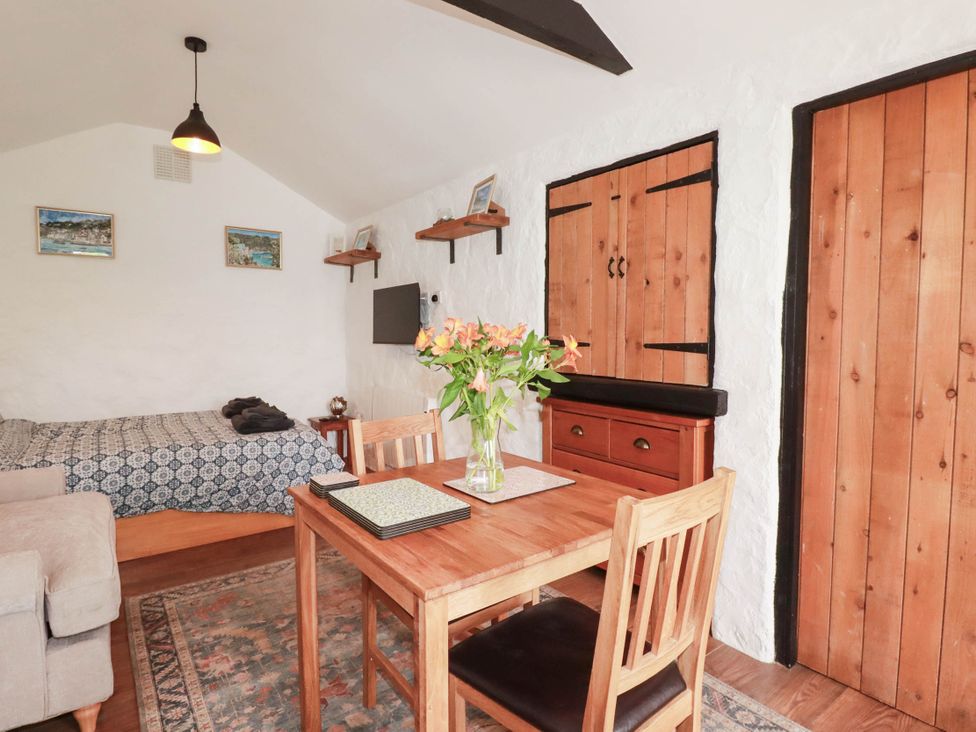 A living room with a bed and dining table at Primrose Cottage in Redruth