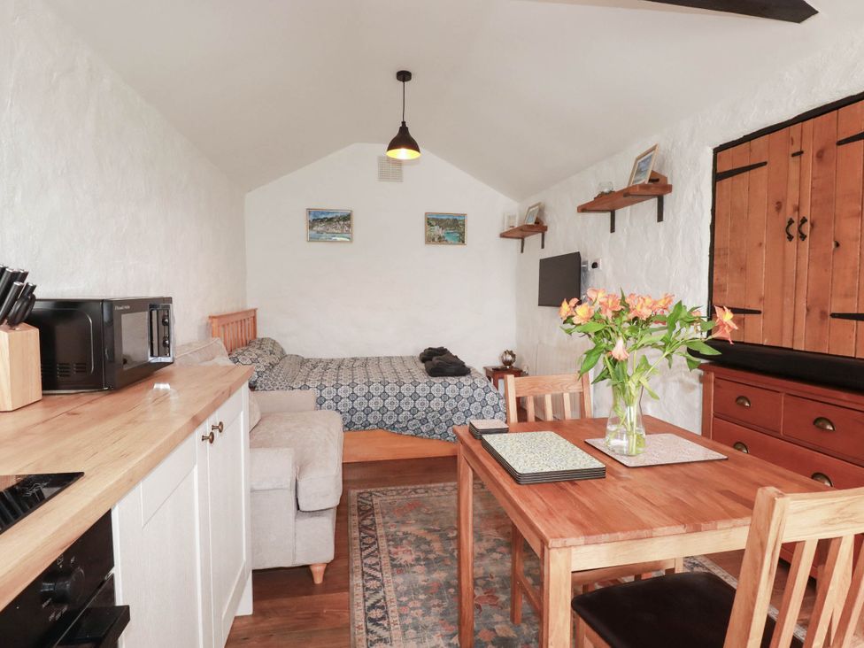A living room with a bed and dining table at Primrose Cottage in Redruth