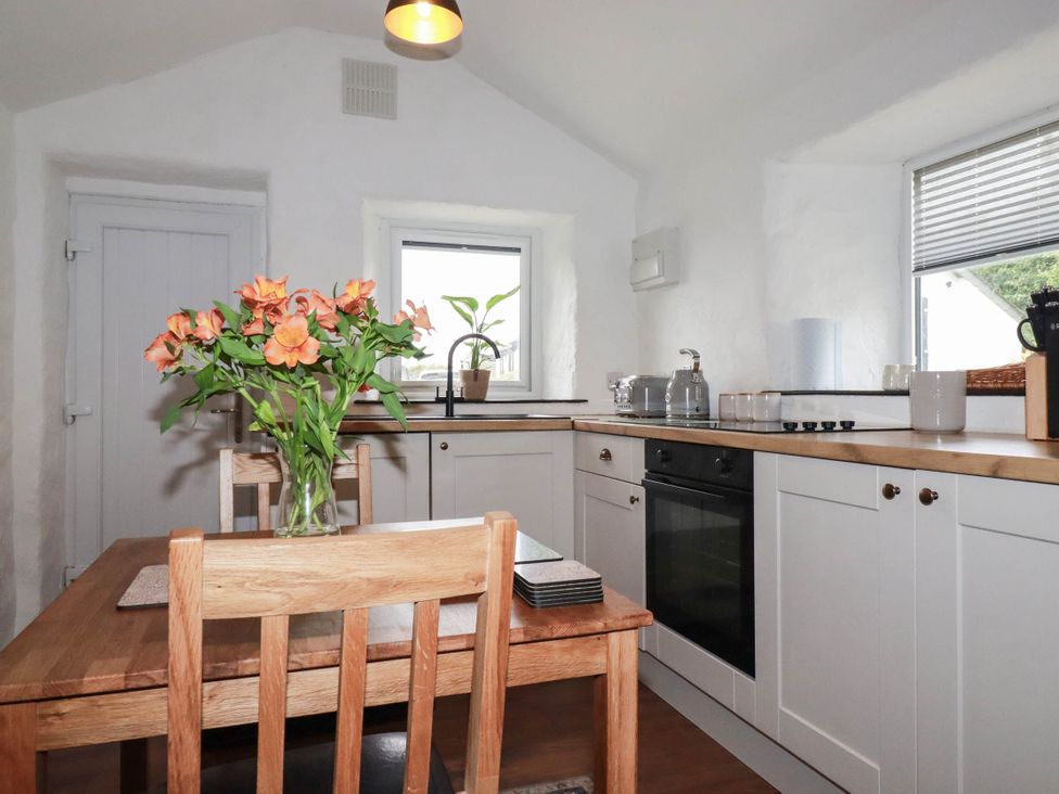 A kitchen with a table and flowers at Primrose Cottage Redruth