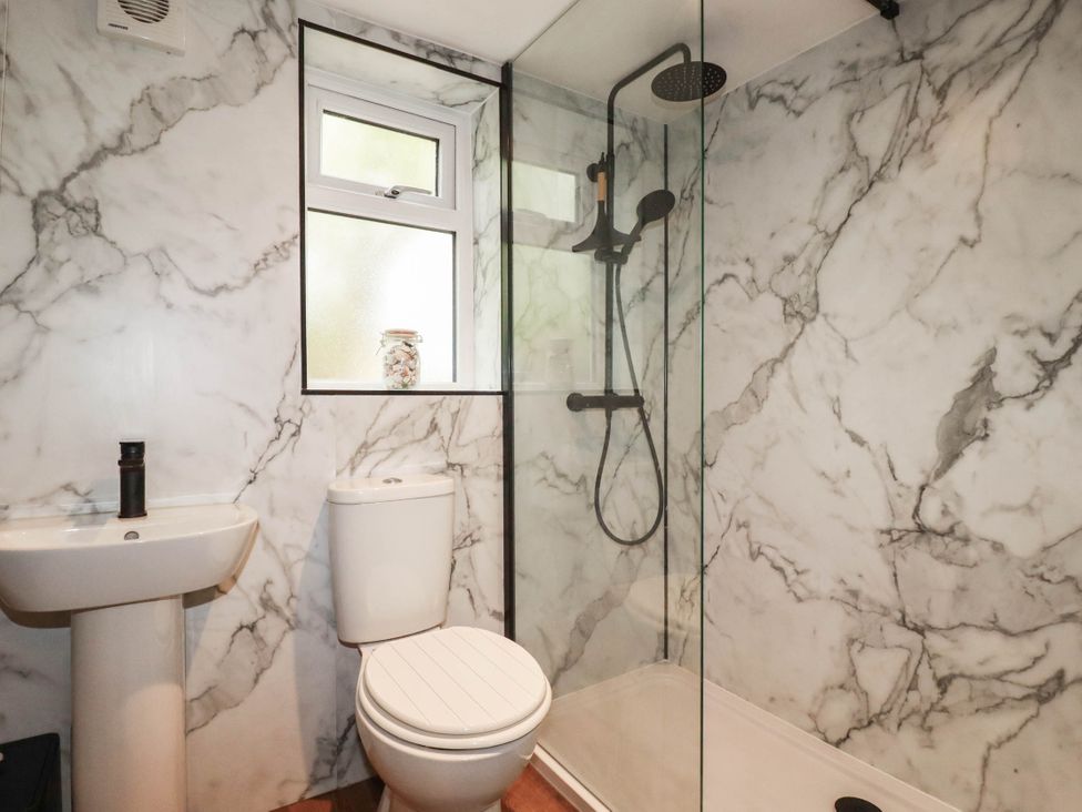 A bathroom with a sink, toilet, and shower at Primrose Cottage, Redruth