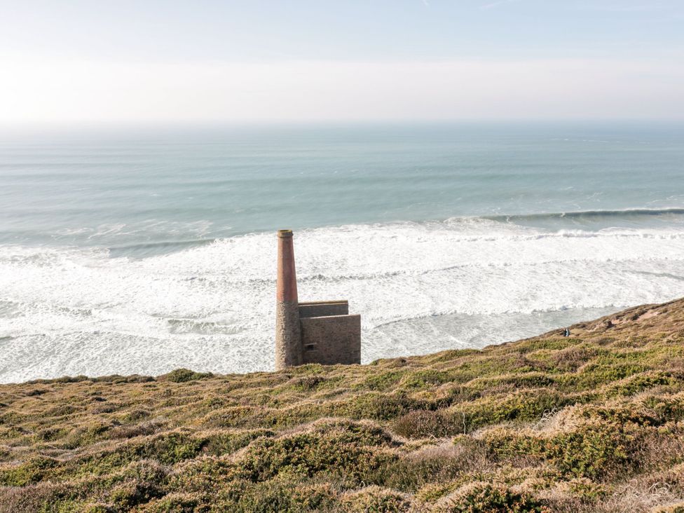 An ocean view with a building and chimney on a hillside at Primrose Cottage Redruth