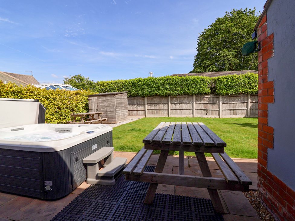 A garden with a hot tub and picnic table at 18 Crewe Road in Crewe