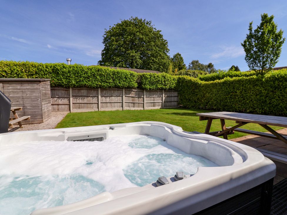 A hot tub in a garden area with fencing and seating at 18 Crewe Road in Crewe