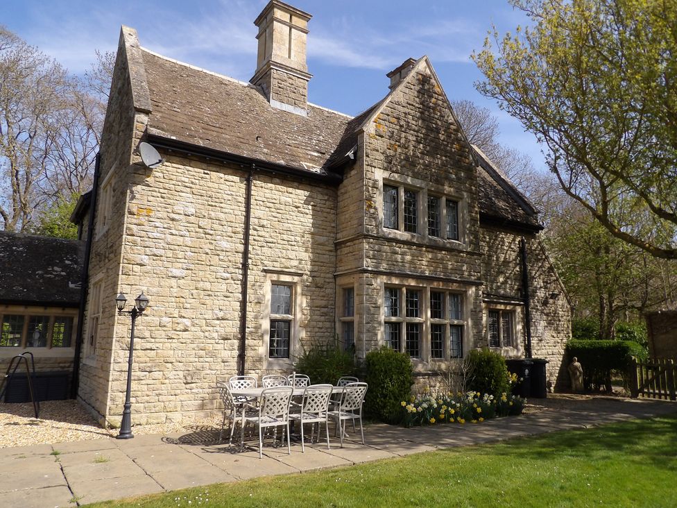 A stone house with a table and chairs in the garden at Greenwood Manor in Peterborough