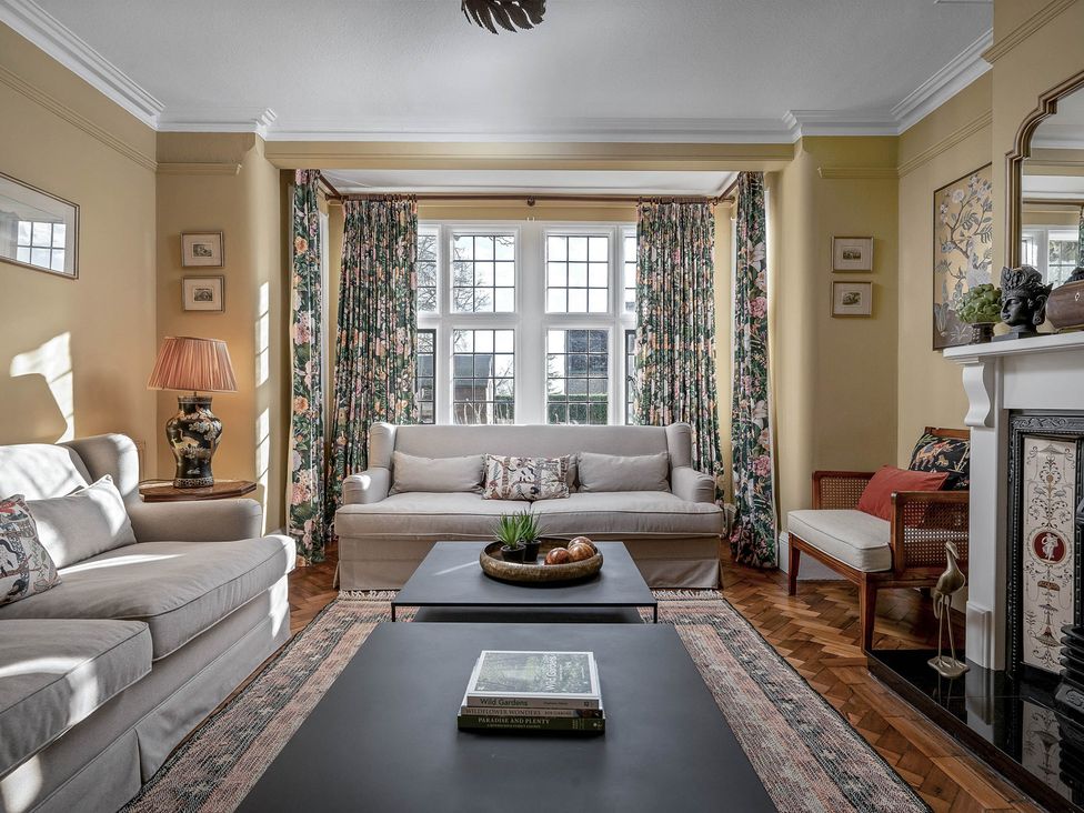 A living room with sofas, a coffee table, and curtains at Greenwood Manor in Peterborough