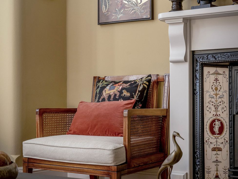 A chair with a cushion and decorative objects next to a fireplace at Greenwood Manor in Peterborough