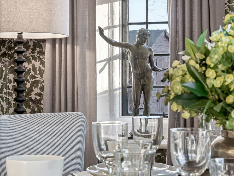 A dining room with a statue by the window at Greenwood Manor in Peterborough
