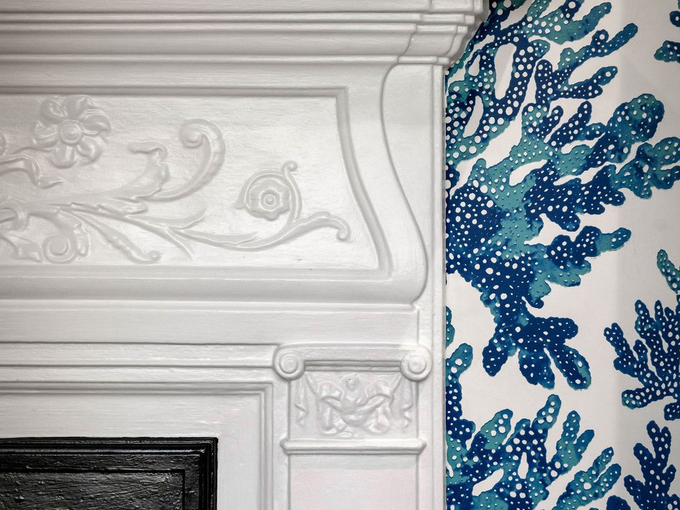 A fireplace with decorative molding and patterned wallpaper at Greenwood Manor in Peterborough