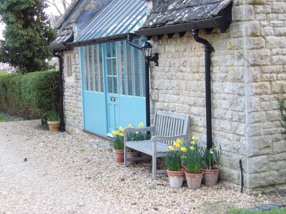 A garden with a bench and flower pots at Greenwood Manor in Peterborough