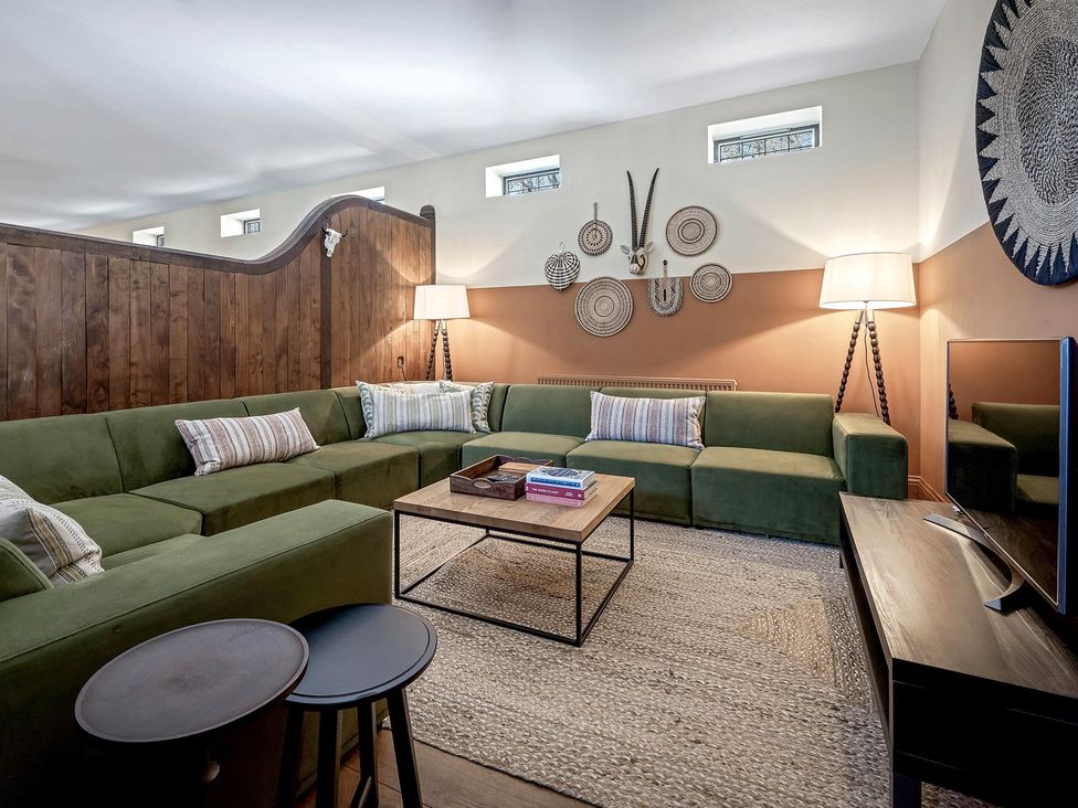 A living room with a green sofa and a coffee table at The Lady Rothschild Stables in Peterborough