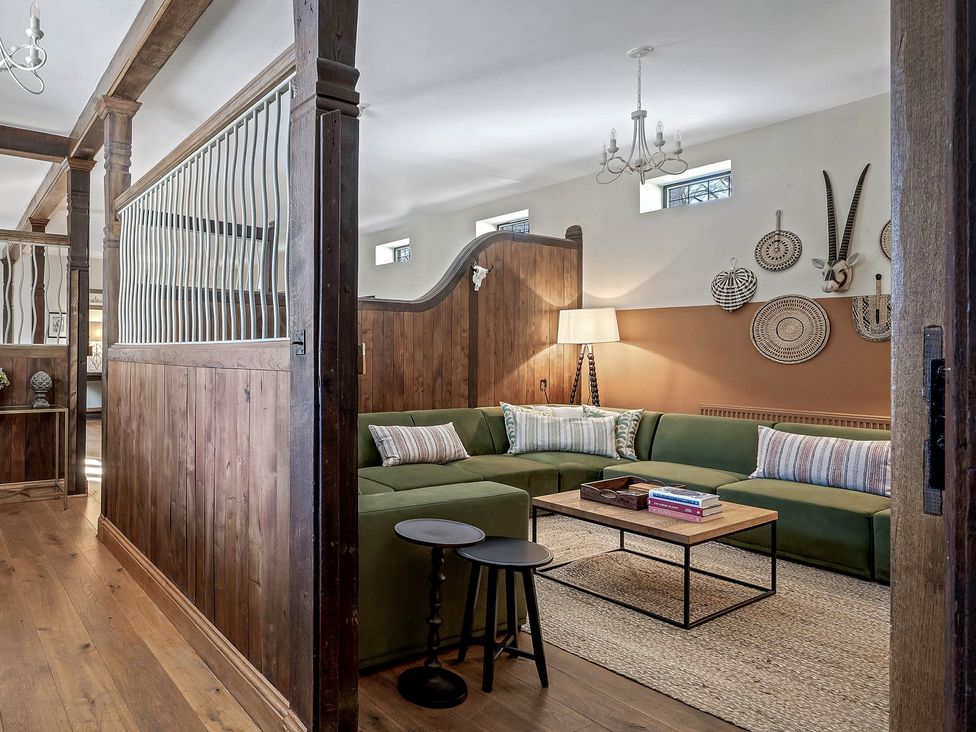 A living room with a green sofa and wooden coffee table at The Lady Rothschild Stables Peterborough