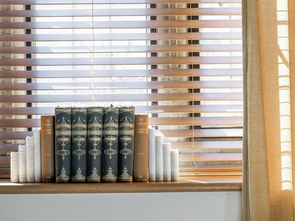 A living room with books and candles on a windowsill at The Lady Rothschild Stables in Peterborough