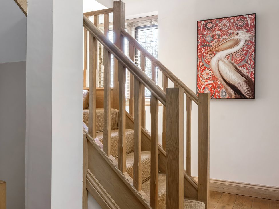 A staircase with wooden railing and artwork at The Lady Rothschild Stables in Peterborough