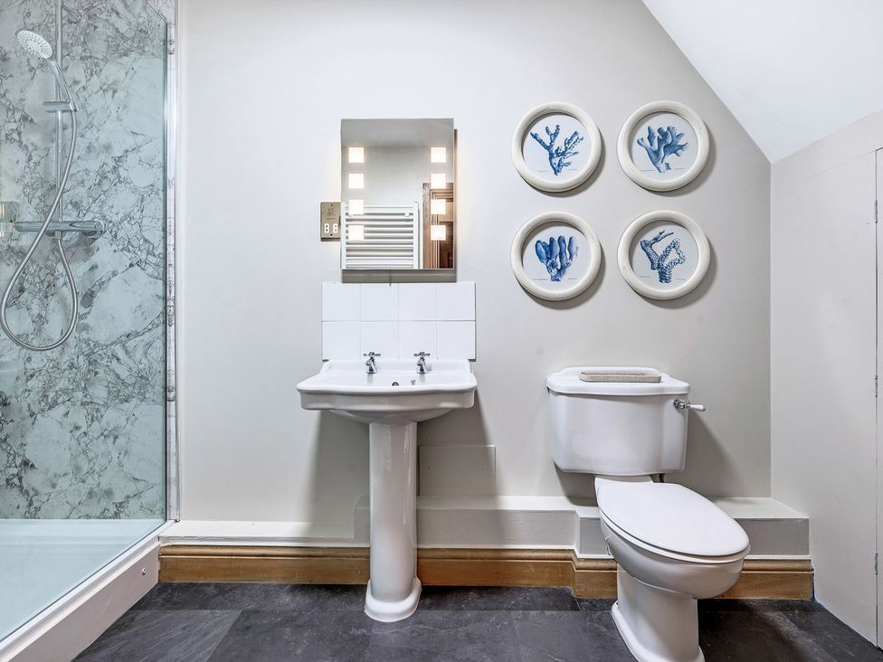 A bathroom with a sink, toilet, shower, and decorative plates at The Lady Rothschild Stables in Peterborough