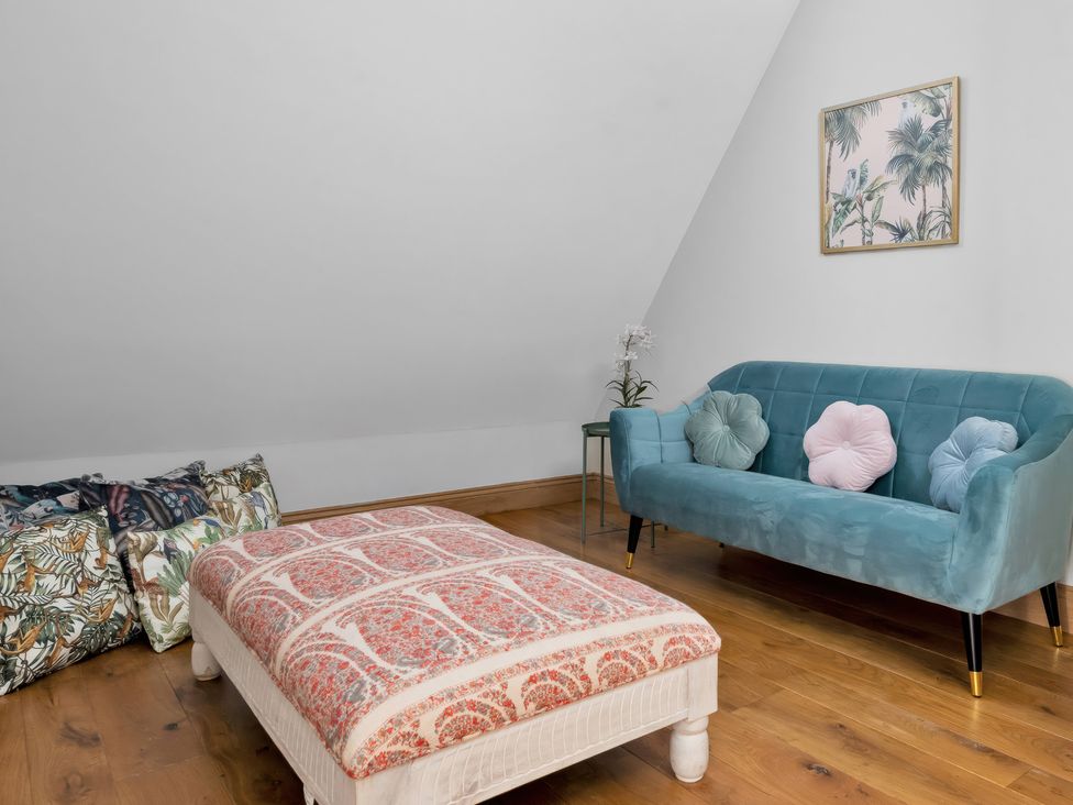 An attic with a sofa and pouffe at The Lady Rothschild Stables in Peterborough