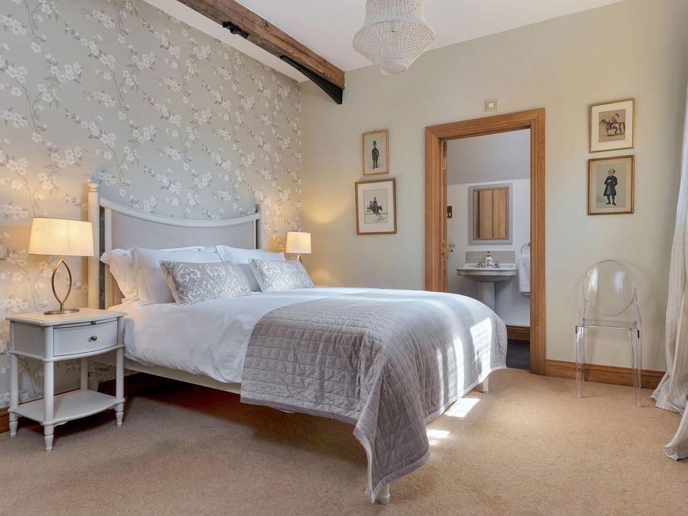 A bedroom with a bed and doorway to a bathroom at The Lady Rothschild Stables Peterborough