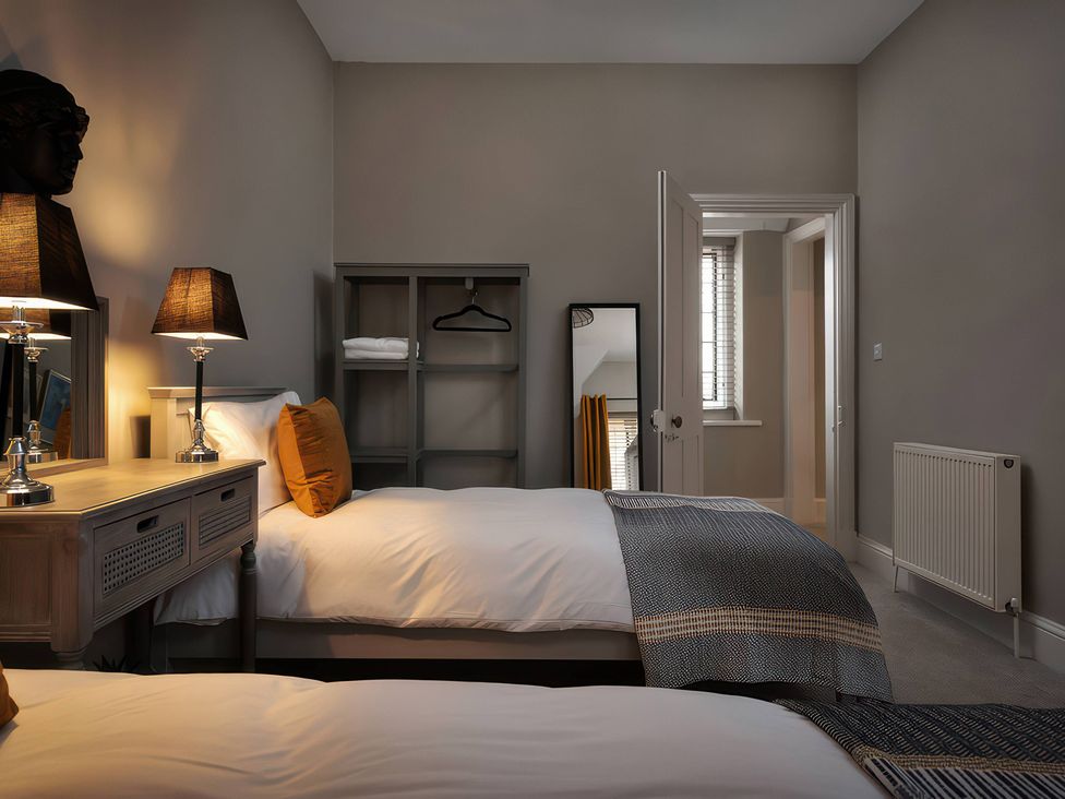 A bedroom with two beds and a side table at The Lady Rothschild Stables in Peterborough