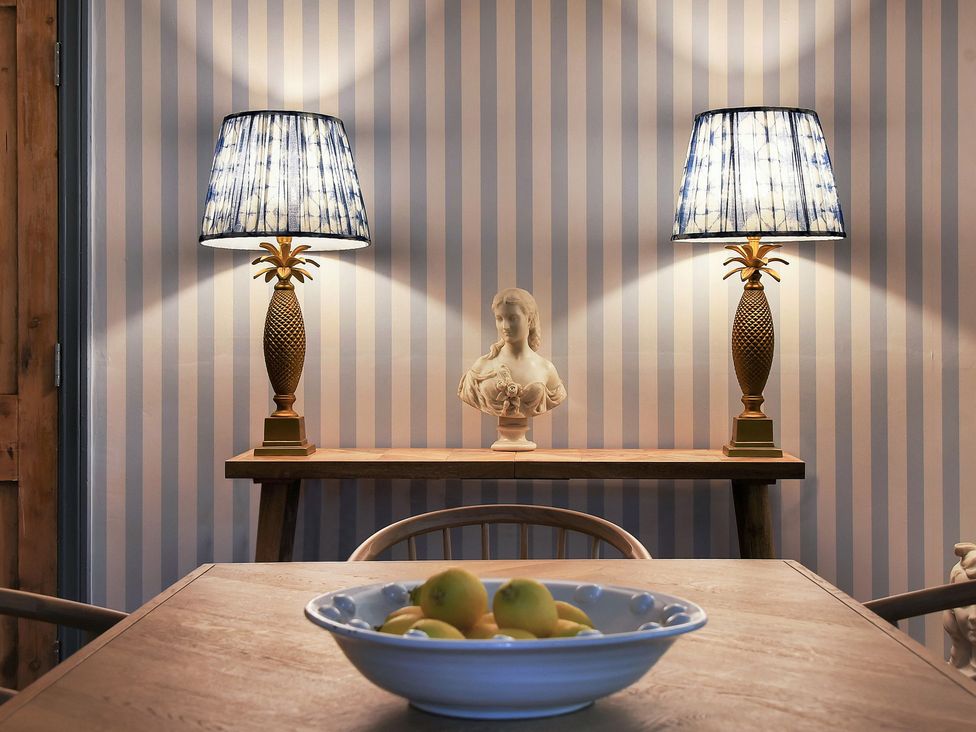 A dining room with lamps and a bowl of fruits at Home Farm Cottage in Peterborough