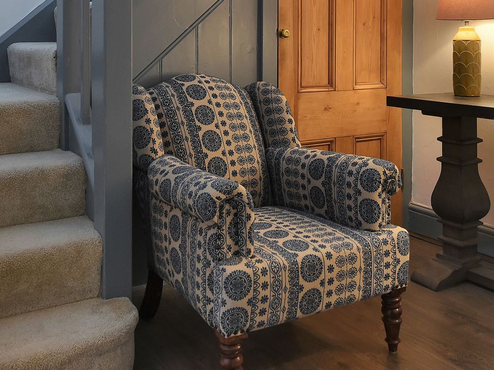 A living room with an armchair, table, and lamp at Home Farm Cottage in Peterborough