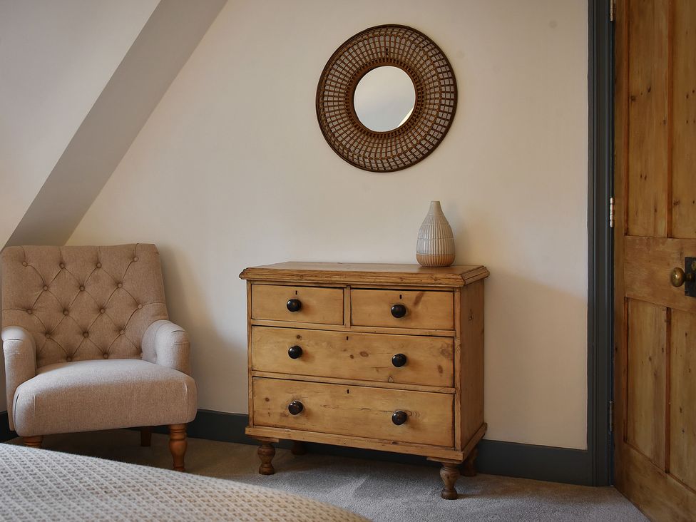 A bedroom with an armchair and a chest of drawers at Home Farm Cottage in Peterborough