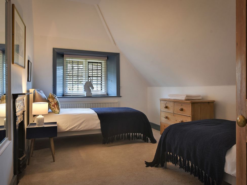A bedroom with two beds and a dresser at Home Farm Cottage in Peterborough
