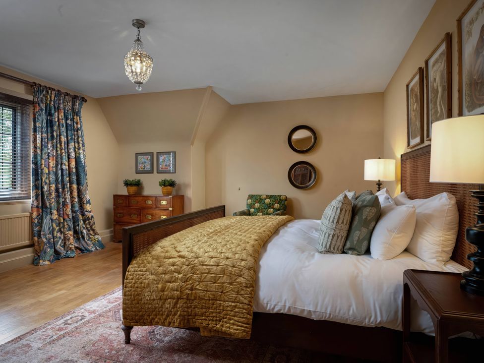 A bedroom with a bed, nightstand, and curtains at Rubens Rooms in Peterborough