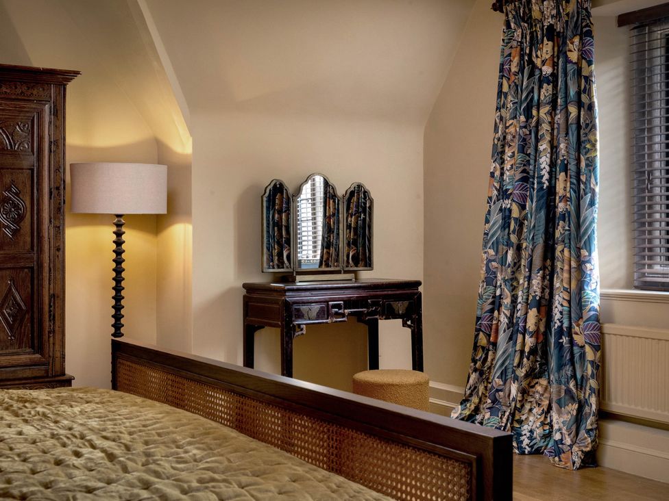 A bedroom with a mirror and lamp at Rubens Rooms in Peterborough