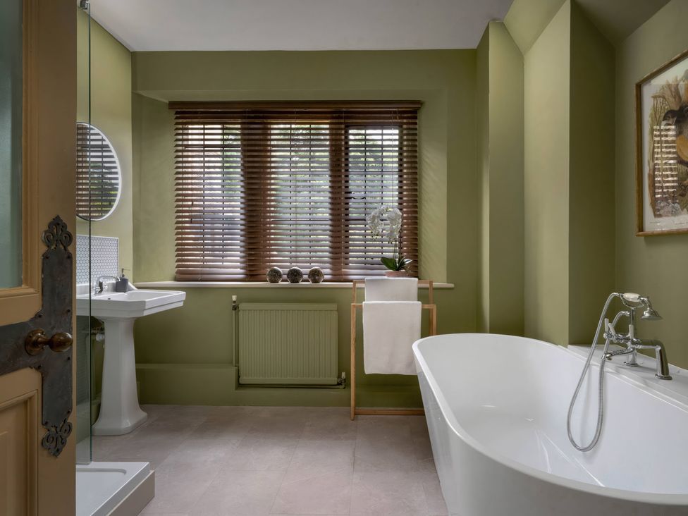 A bathroom with a bathtub, sink, and window at Rubens Rooms, Peterborough