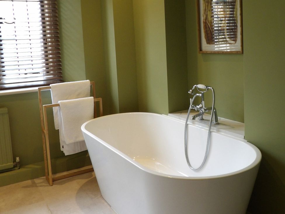 A bathroom with a bathtub and towel rack at Rubens Rooms in Peterborough