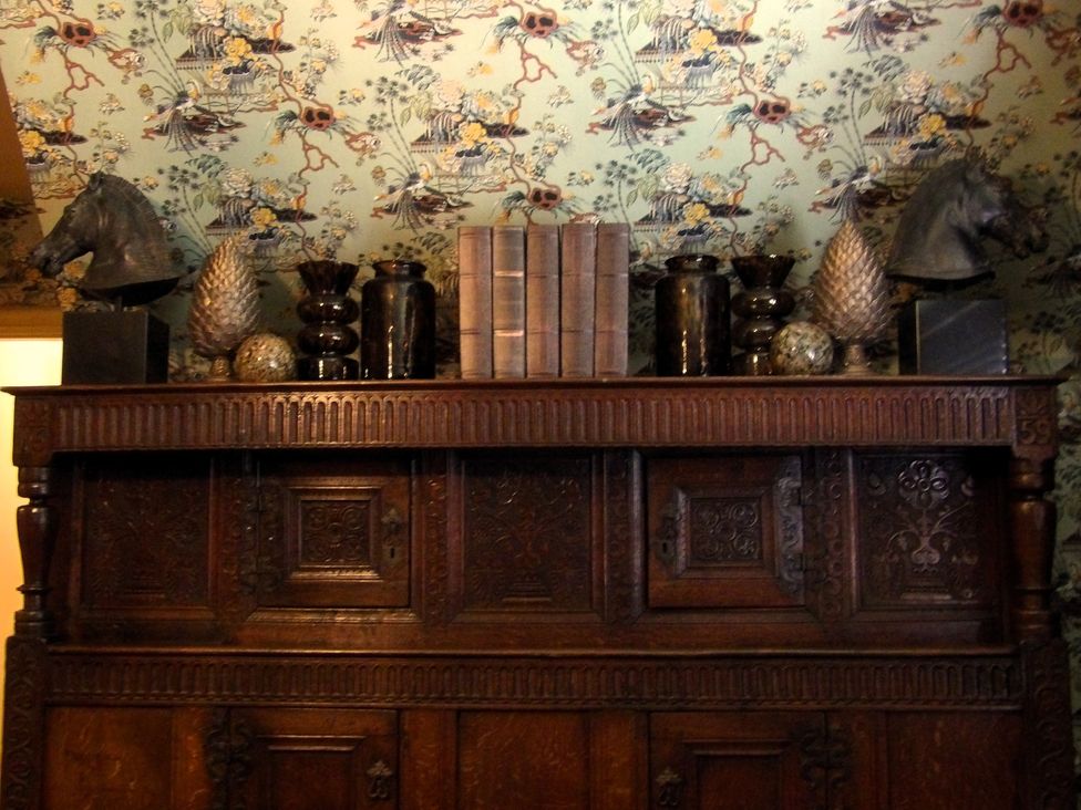 A wooden cabinet with decorative items and books at Rubens Rooms in Peterborough