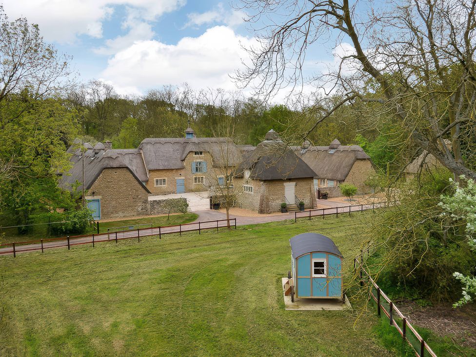 A view of a stone building with a thatched roof and shed at The Lady Rothschild Dairy in Peterborough