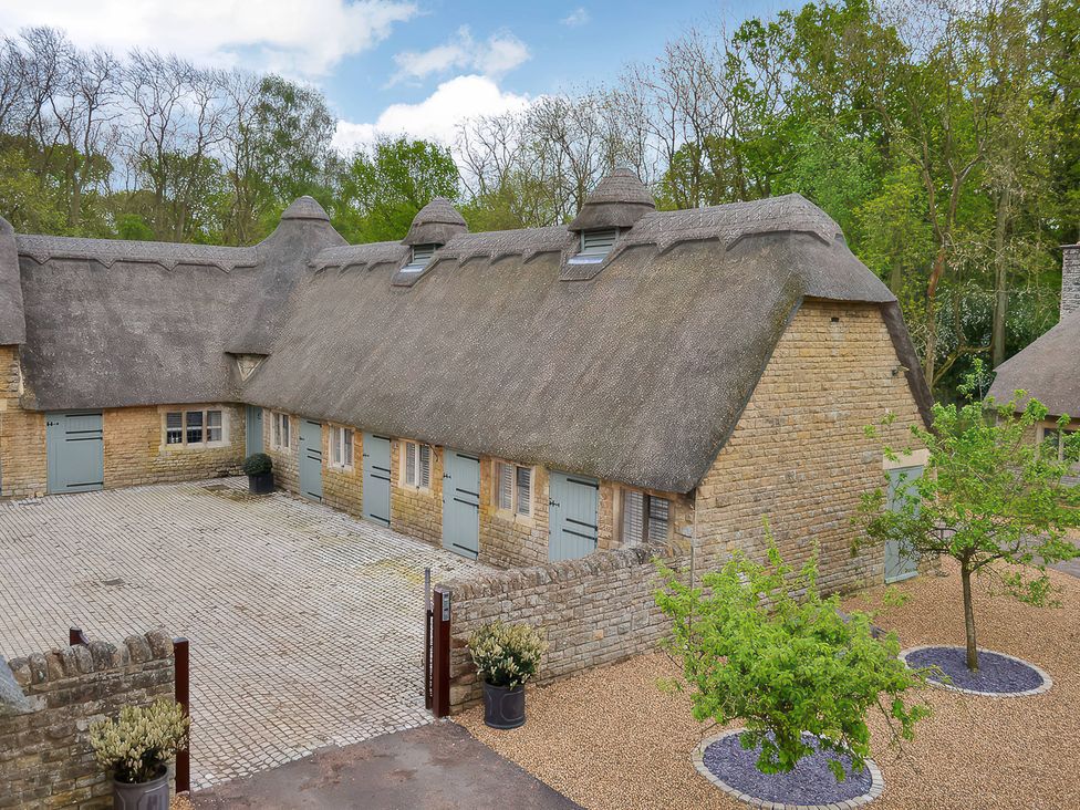 A stone building with a thatched roof and courtyard at The Lady Rothschild Dairy in Peterborough