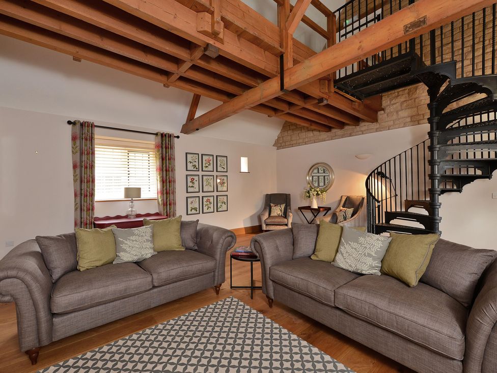 A living room with sofas and a spiral staircase at The Lady Rothschild Dairy in Peterborough