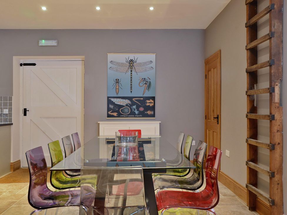 A dining room with a glass table and colorful chairs at The Lady Rothschild Dairy in Peterborough