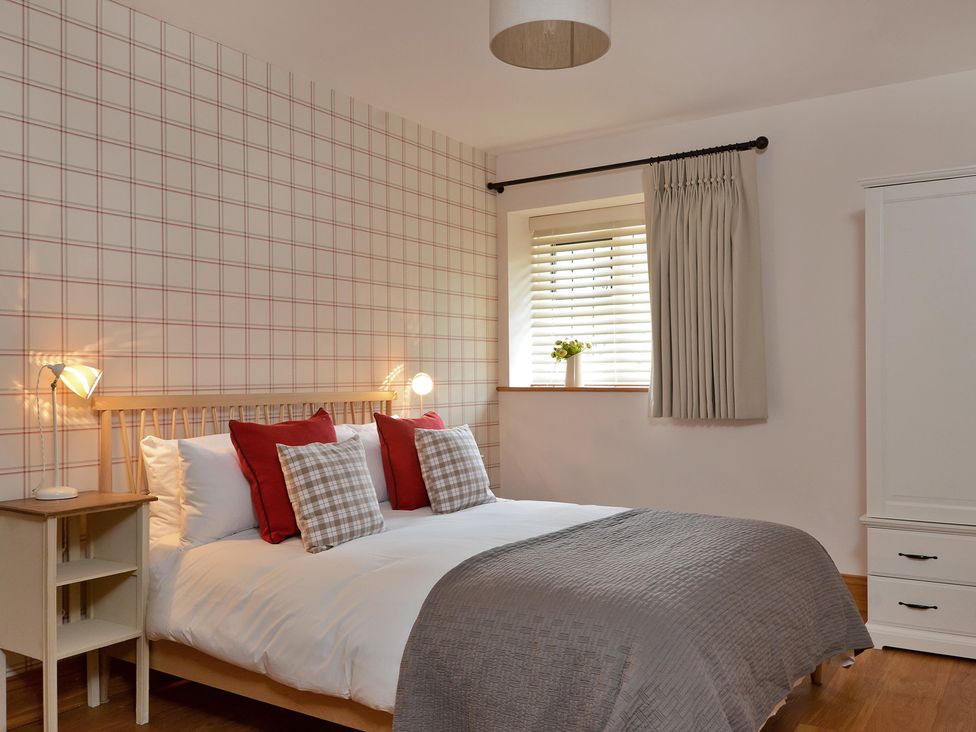 A bedroom with a bed and bedside table at The Lady Rothschild Dairy in Peterborough