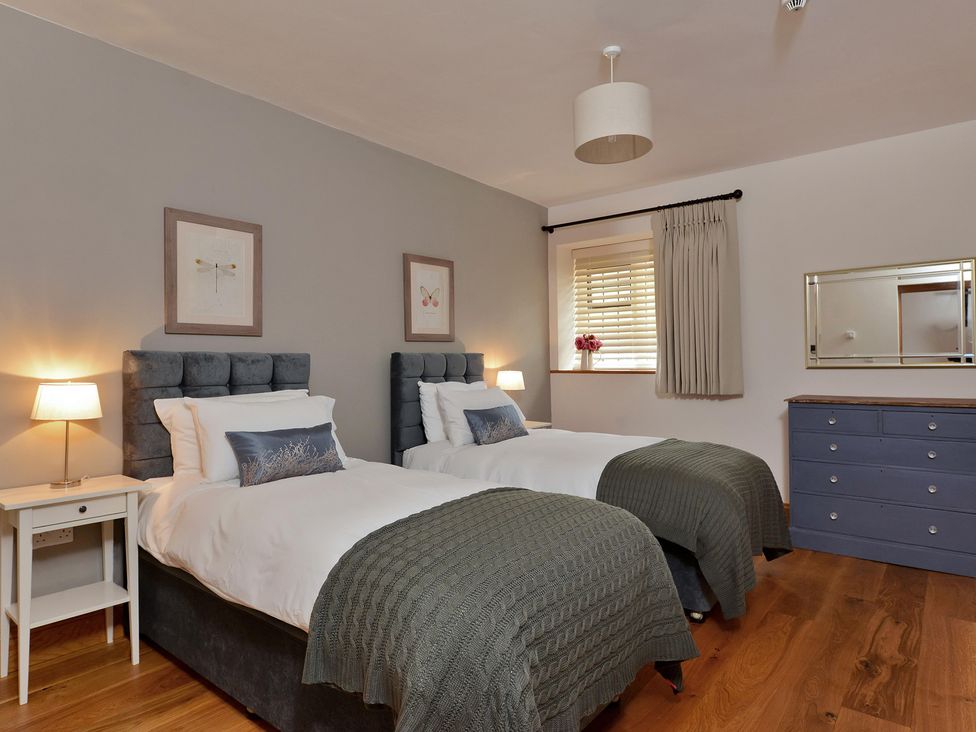 A bedroom with two beds and a nightstand at The Lady Rothschild Dairy in Peterborough