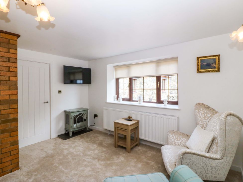 A living room with a television and an armchair at Cil Y Coed in Star near Llanfairpwllgwyngyll