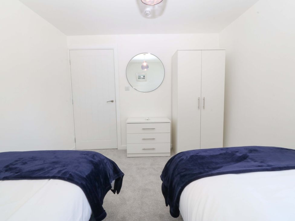A bedroom with two beds, a dresser, a wardrobe and a mirror at Cil Y Coed in Star near Llanfairpwllgwyngyll