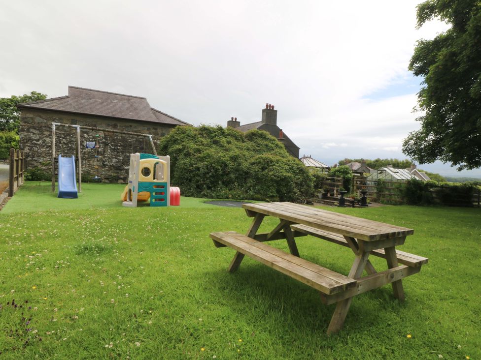 A garden with a picnic table and playground equipment at Cil Y Coed Star near Llanfairpwllgwyngyll