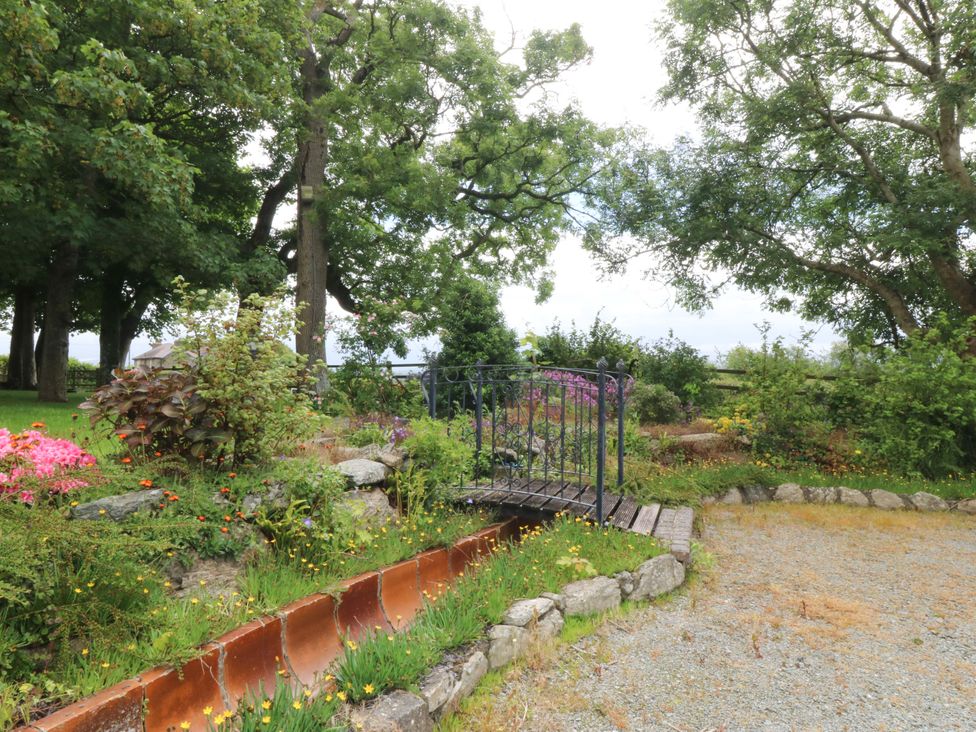 A garden with a bridge and flowers at Cil Y Coed Star near Llanfairpwllgwyngyll