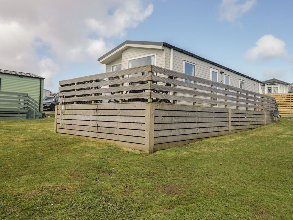 A caravan with a fence and grass area at Standard Caravan at Three Lochs Holiday Park Newton Stewart